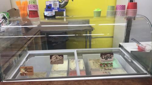 A glass display case filled with various ice cream flavors, including Butter Pecan, Coffee, and Strawberry.