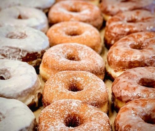 A variety of donuts in different flavors and glazes arranged neatly on a tray.