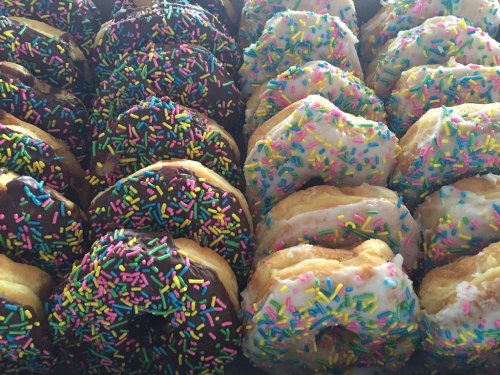 A variety of colorful donuts with chocolate and white icing, topped with vibrant sprinkles.