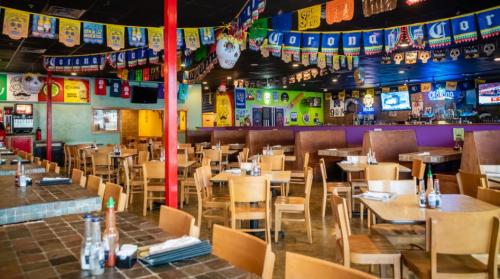 A vibrant restaurant interior with wooden tables, colorful banners, and a lively atmosphere.