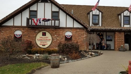 Exterior of Valley Vineyards Winery and Brewery, featuring brick walls, flags, and decorative bunting.