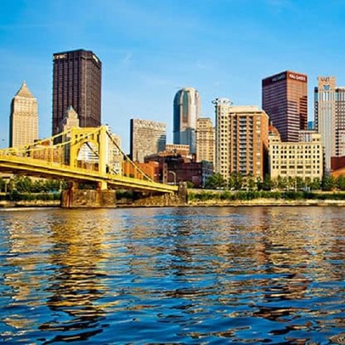 A vibrant city skyline with tall buildings reflected in a river, featuring a yellow bridge in the foreground.