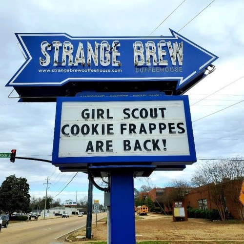 Sign for Strange Brew Coffeehouse announcing "Girl Scout Cookie Frappes are back!" with an arrow pointing.