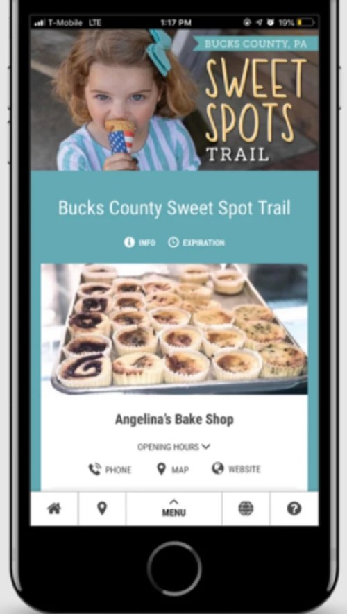 A child eating ice cream, with a mobile screen displaying the Bucks County Sweet Spot Trail and Angelina's Bake Shop info.