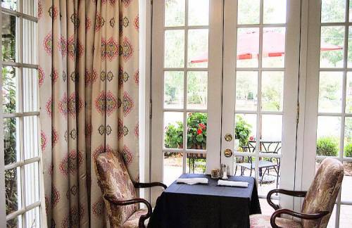 Cozy restaurant corner with a table set for two, surrounded by elegant curtains and a view of outdoor seating.