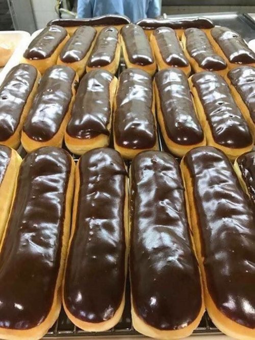 A tray of freshly baked chocolate-covered long donuts arranged in neat rows.