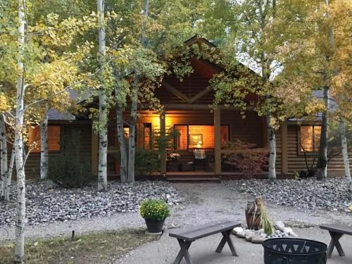 A cozy wooden cabin surrounded by trees, with warm lights glowing from the windows and a stone pathway leading up.