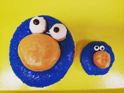 Two donuts decorated to resemble a blue cartoon character, one large and one small, with eyes and a round orange nose.