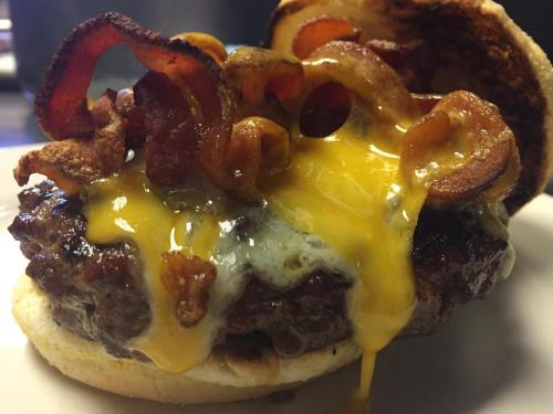 Close-up of a juicy cheeseburger topped with crispy bacon and melted cheese, served on a toasted bun.