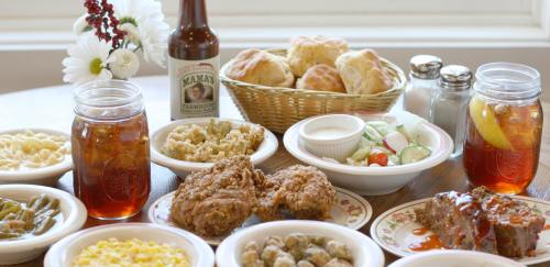 A spread of Southern comfort food including fried chicken, biscuits, sides, and sweet tea on a wooden table.