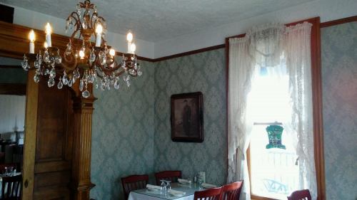 Cozy dining room with a chandelier, vintage decor, and a window draped in lace curtains.