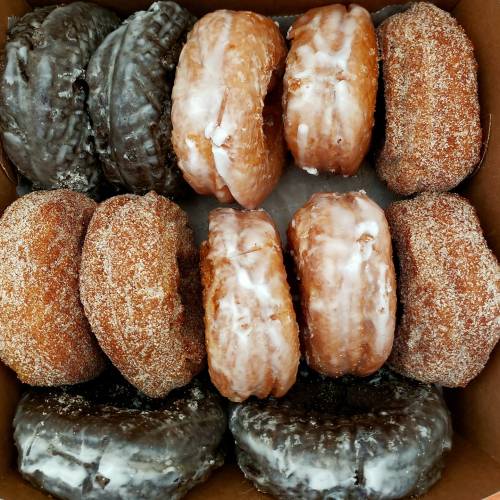 A box of assorted donuts: glazed, cinnamon sugar, and chocolate-covered varieties arranged neatly.