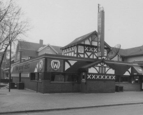Black and white photo of a building with a distinctive Tudor-style design, featuring a sign for "Street Brats."