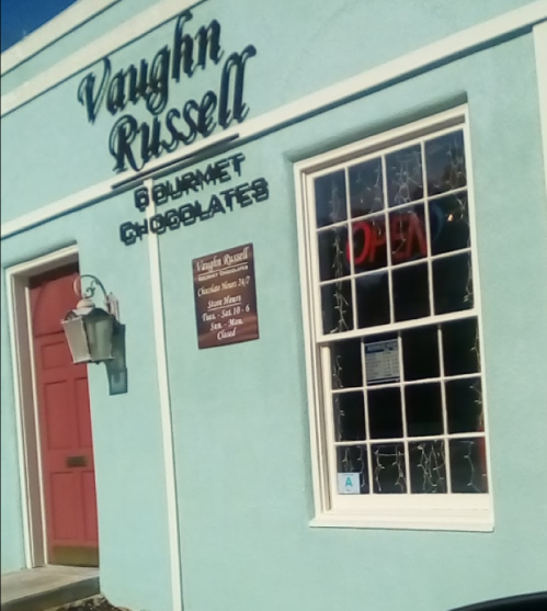 Exterior of Vaughn Russell Gourmet Chocolates, featuring a blue building, open sign, and a decorative window.