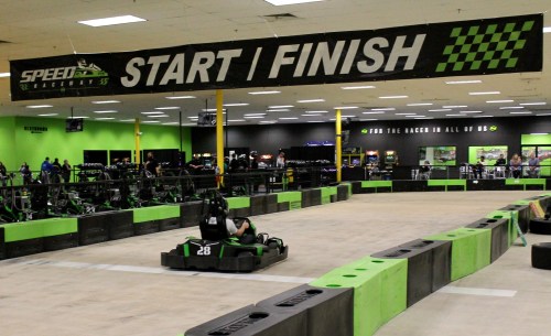 Indoor go-kart track with a "START / FINISH" banner, featuring green and black decor and karts on the track.