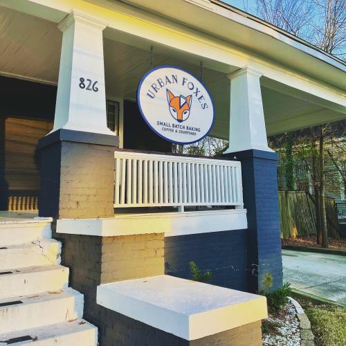 Sign for "Urban Foxes" hangs from a porch, featuring a fox logo and text about small batch baking and coffee.