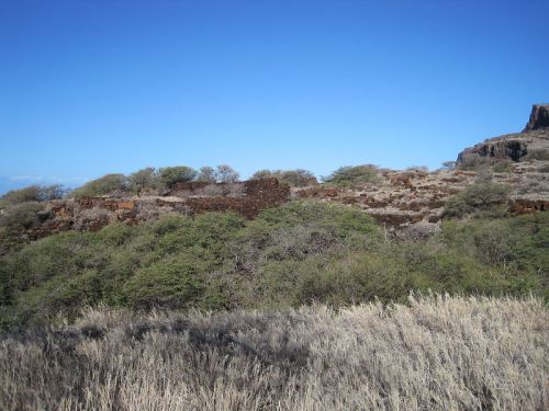 A landscape featuring rocky terrain, sparse vegetation, and a clear blue sky.