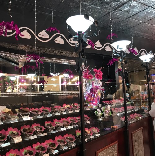 A beautifully decorated chocolate shop with colorful displays and festive decorations hanging from the ceiling.