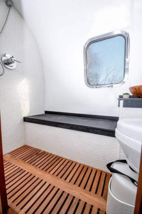 A modern bathroom featuring a wooden floor, a toilet, and a window with natural light.