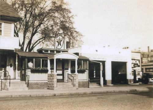 Historic black-and-white photo of a vintage gas station with a diner, featuring a prominent Texaco sign.