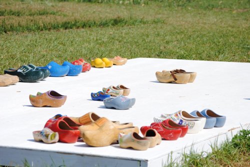 A variety of colorful wooden clogs arranged on a white platform, set against a grassy background.