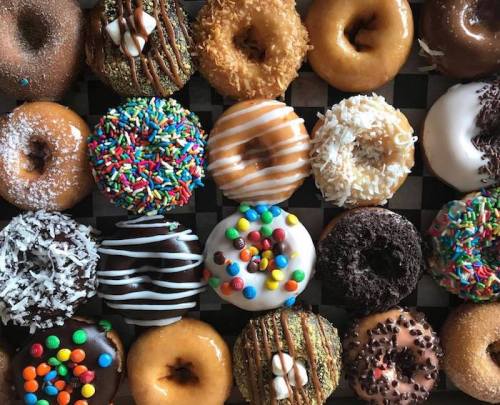 A colorful assortment of donuts with various toppings arranged on a checkered background.