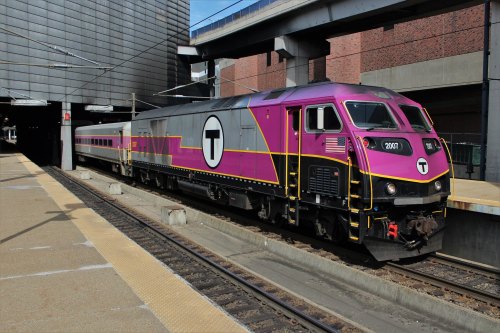 A purple and black commuter train at a station, with a sleek design and the letter "T" prominently displayed.