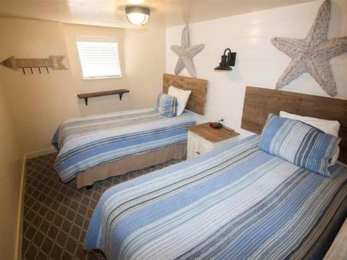 Cozy bedroom with two twin beds, blue striped bedding, starfish decor, and a small nightstand.