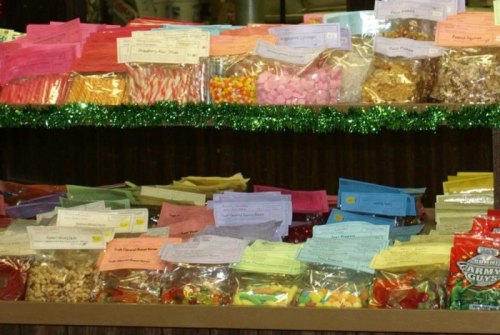 A colorful display of assorted candies and snacks in clear bags, labeled with various flavors and types.