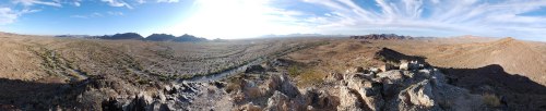 A panoramic view of a vast desert landscape with mountains in the distance and a clear blue sky.