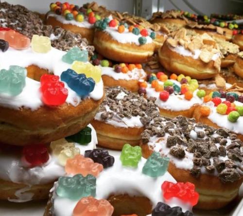 A colorful assortment of decorated donuts topped with gummy bears, cereal, and vibrant candy.