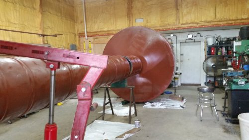 A large, cylindrical metal object in a workshop, with tools and equipment visible in the background.
