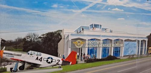 A historic airplane in front of the Mississippi Aviation Heritage Museum, showcasing aviation history and visitors.