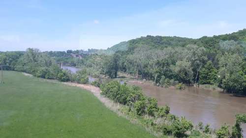 A scenic view of a river winding through lush greenery and trees under a clear blue sky.