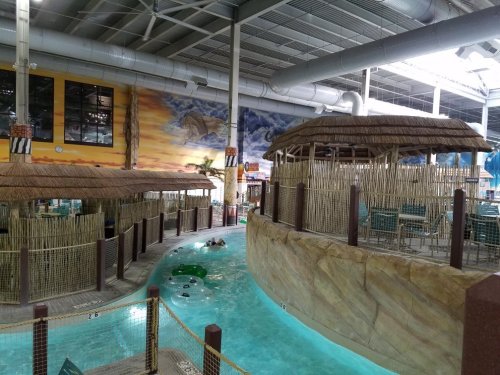 Indoor water park featuring a lazy river, thatched huts, and tropical-themed decor.
