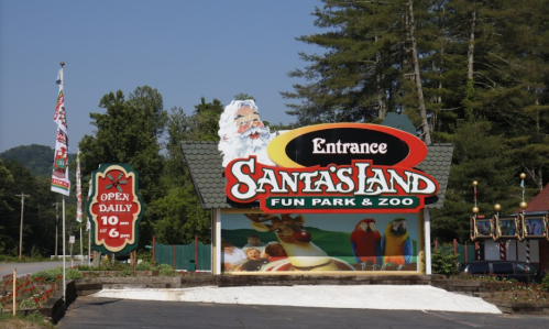 Sign for Santa's Land Fun Park & Zoo, featuring a Santa figure, with hours and entrance details. Lush greenery in the background.