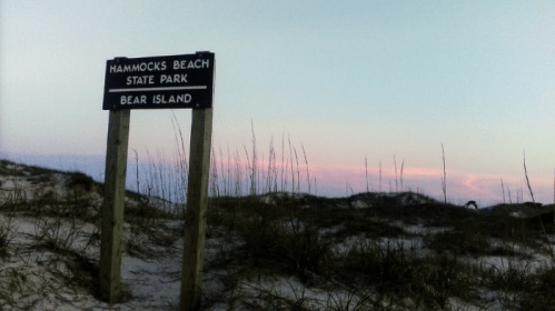 Sign for Hammocks Beach State Park, Bear Island, with sandy dunes and a pastel sky in the background.