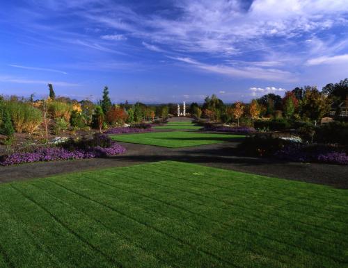A vibrant garden with lush green lawns, colorful flower beds, and a clear blue sky in the background.