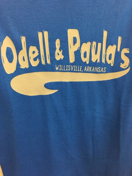 Blue shirt with the text "Odell & Paula's" and "Willisville, Arkansas" in white lettering.