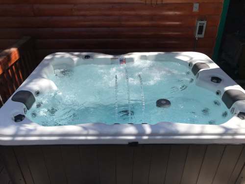 A hot tub filled with water, featuring jets and a wooden deck in a cozy outdoor setting.