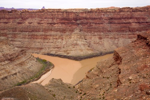 A winding river flows through a deep canyon with layered rock formations in earthy tones.