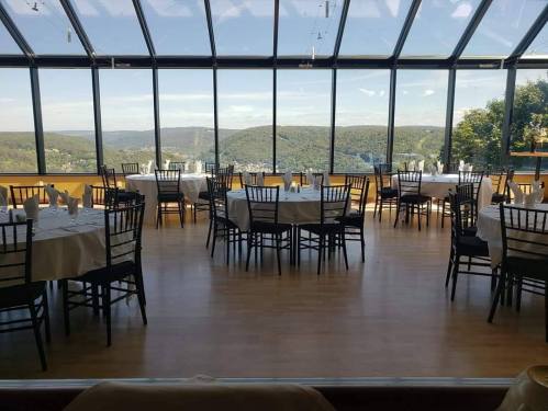A spacious dining area with tables set for guests, featuring large windows overlooking a scenic landscape.