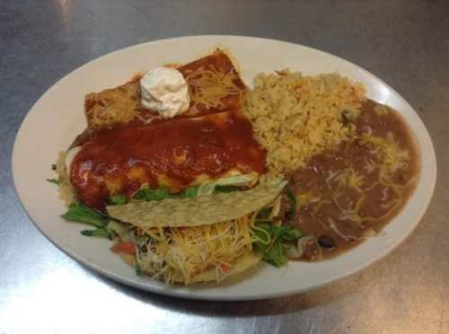 A plate featuring enchiladas with sauce, a taco, rice, refried beans, and a dollop of sour cream.
