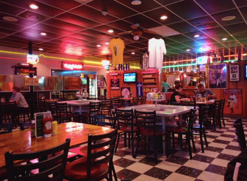 A vibrant diner interior with checkered floors, colorful lights, and patrons dining at wooden tables.