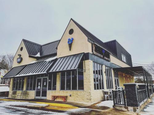A modern building with a black metal roof and stone facade, featuring a blue panda logo and outdoor seating.