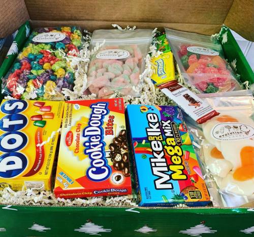A festive box filled with various candies, including gummies, cookie dough bites, and colorful popcorn.