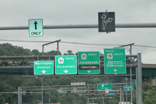 Traffic signs indicating directions to Uniontown, Downtown, and Dormont, with a green light for straight movement.