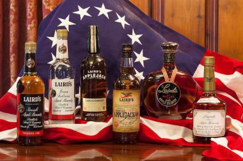 A collection of Laird's apple brandy bottles displayed in front of an American flag.