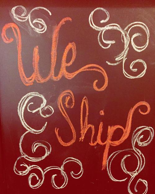 Chalkboard art with the text "We Ship" surrounded by decorative swirls in orange and white on a red background.