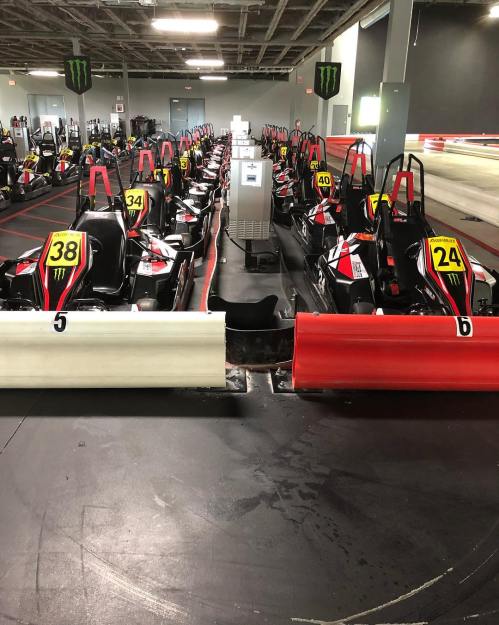 A go-kart track with multiple karts lined up, featuring numbered karts and a barrier separating the lanes.